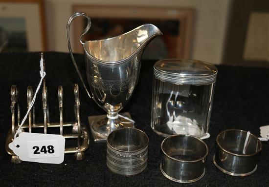 Georgian silver cream jug, silver four-division toast rack, 3 napkin rings & silver-mounted toilet jar